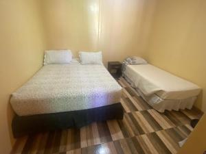 a small bedroom with two beds and a wooden floor at Estrella Ancestral 1 in San Pedro de Atacama