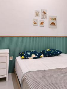 a bed with blue pillows and a green wall at Villa Dino Park Batu in Karangploso