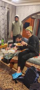 a woman sitting on a bed holding a plate of food at Id villa cottage in Tangmarg