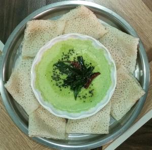 a plate with a bowl of green dip and some bread at Coconut Village Resort in Alībāg