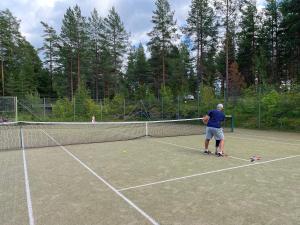 a man standing on a tennis court with a racket at Loma-aika in Vierumäki +4 photos