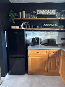 a kitchen with a black refrigerator and wooden cabinets at The Flower Loft in Yeovil