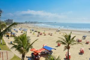 a beach with a bunch of people and the ocean at Exelente Localiazação - 50m Enseada e Pitangueiras - Apt Saint Patrick in Guarujá