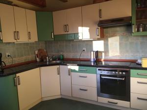 una cucina con armadi verdi e bianchi e forno di Idylla - Cottage in Lower Silesia a Duszniki Zdrój
