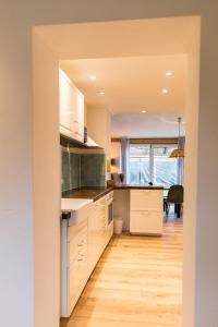 a kitchen with white cabinets and a wooden floor at Ferienhaus am Eichberg in Grabenstätt +13 photos