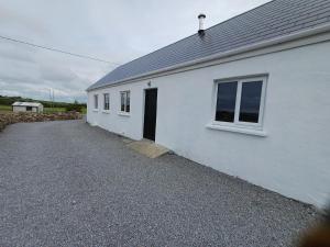 a white building with a door and a driveway at Lavender lane cottage in Tralee
