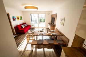 a living room with a table and a red couch at Apartment Motzenhof - Stadtnähe Salzburg - modernes Bauernhoferlebnis inklusive in Adnet