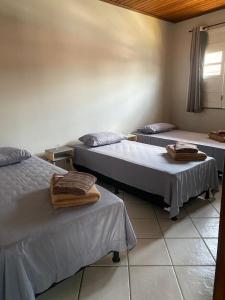 a room with three beds with towels on them at Apartamento Day in Ilhéus