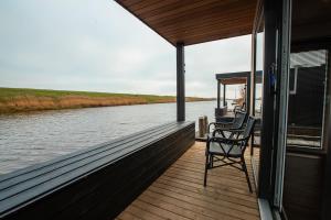 a boat deck with a chair on the water at Tiny Boat House #5 in Garnwerd