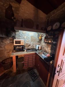a small kitchen with a microwave and a sink at Abrigo das Penhas in Manteigas +9 photos