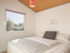 a white bedroom with a bed and a window at Lundenbergsand in Simonsberg