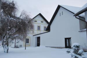 una casa blanca con techo negro en la nieve en Dvůr U kapličky, en Žďár nad Sázavou