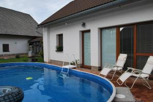 a swimming pool with chairs and a house at Dvůr U kapličky in Žďár nad Sázavou