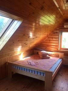 a bed in the attic of a wooden cabin at Guest house Pīlādzis in Čornaja