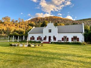 a white house with a hill in the background at De Kleine Kaap Guesthouse in Lady Grey