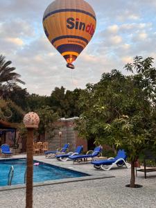 a hot air balloon flying over a swimming pool at El Juneina Villas in Luxor