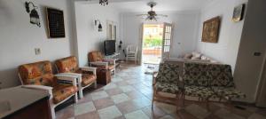 a living room with chairs and a couch and a tv at Spacious Villa with Pool and Sea View in Dawwār ‘Abd Allāh +5 photos