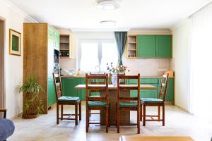 a kitchen with green cabinets and a table and chairs at Rizling Vendégház in Balatonrendes