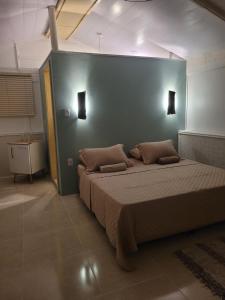 a bedroom with a large bed with a blue wall at Suíte Cambucá in Praia do Bananal