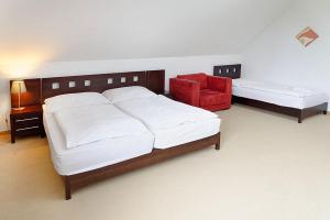 a bedroom with a bed and a red chair at Hotel Tulipan in Tatranská Lomnica