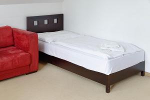a bed and a red couch in a room at Hotel Tulipan in Tatranská Lomnica