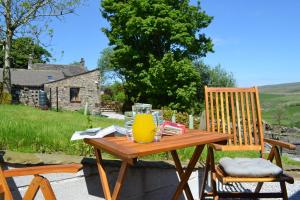 a wooden table with a glass of orange juice on it at The Warren Lodge Cabin at Ashes Farm, Horton in Ribblesdale, Settle in Settle