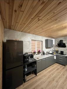 a kitchen with a black refrigerator and wooden ceilings at mountain house in Skhidnitsa +5 photos