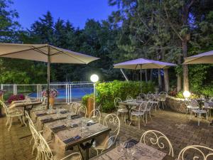 un patio con tavoli, sedie e ombrelloni di ibis Brignoles Provence Verte a Brignoles