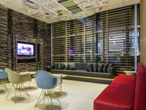 a lobby with a couch and chairs and a tv at ibis Uberaba in Uberaba