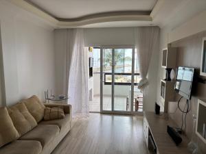 a living room with a couch and a sliding glass door at Vista para o molhe in Itapema