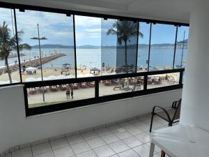 a view of a beach from a room with windows at Vista para o molhe in Itapema