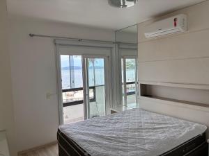 a bedroom with a bed with a view of the ocean at Vista para o molhe in Itapema