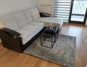 a living room with a white couch and a table at Apartman Hilandarska in Lukavica