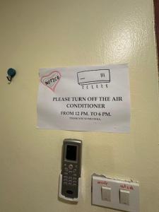 a sign hanging on a wall with a cell phone at Tnon Samui Hostel in Chaweng
