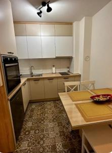 a kitchen with white cabinets and a table at Apartman Hilandarska in Lukavica