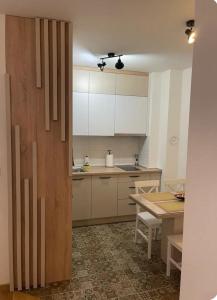 a kitchen with white cabinets and a table at Apartman Hilandarska in Lukavica