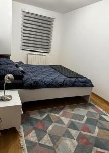 a bedroom with a bed and a rug at Apartman Hilandarska in Lukavica