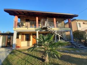 a house with a balcony and a palm tree at Casa Scova, entire apartment in Garlasco