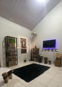 a living room with a tv on a white wall at Morada Amor & Cura Xamanismo in Mongaguá