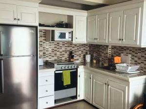 a kitchen with white cabinets and a stove and a refrigerator at Ocean Grace - Canouan Island in Canouan