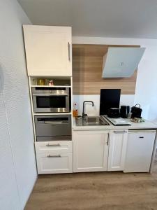 a kitchen with white cabinets and a laptop on the counter at Studio Cosy et élégant avec Terrasse in Caluire-et-Cuire