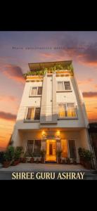 a large white building with a sunset in the background at Shree Guru Ashray in Ujjain
