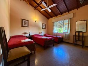 a room with two beds with red sheets and a window at Hotel Siena Pinamar in Pinamar