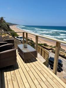 a deck with a table and chairs and the beach at Khayalena Beach House - Tides Reach in Umdloti