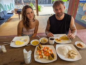 a man and a woman sitting at a table with food at Sand Dune Beach Hotel & Surf Camp in Arugam Bay
