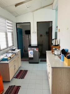 a kitchen with a refrigerator in the middle of a room at Homestay Hayyan in Kampong Terbak