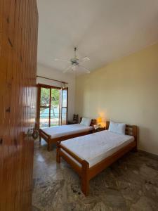 a bedroom with two beds and a ceiling fan at Cherronisi Apartments in Áyios Andréas