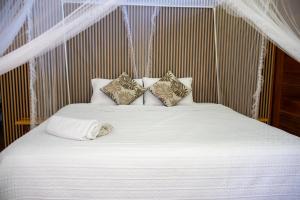 een bed met witte lakens en kussens bij Valencia Lake Lodge in Puerto Maldonado