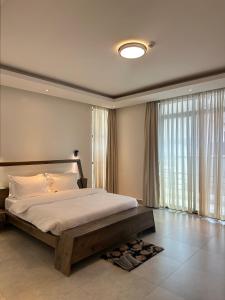 een slaapkamer met een groot bed en een groot raam bij Residence Gratia by Eagle View in Kigali