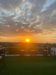 a sunset on a balcony with tables and chairs at Ayoolasudi in Kerobokan